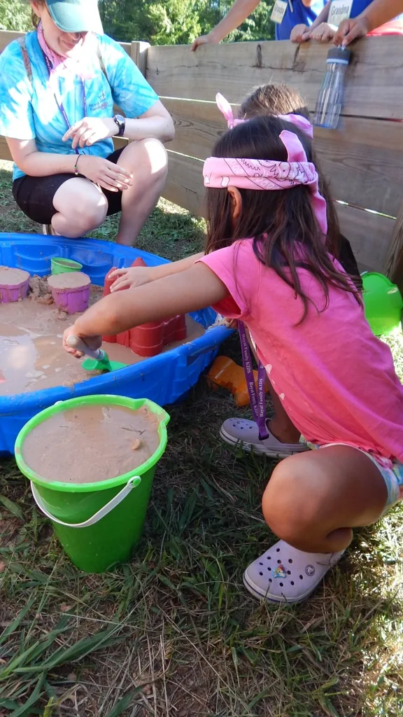 A camper carrying a bucket across the field at camp